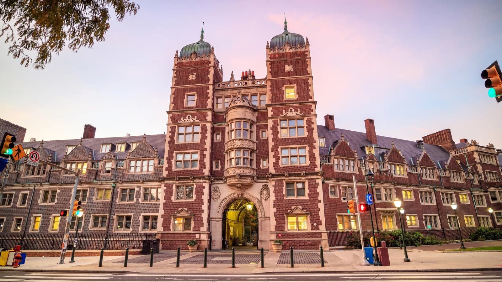 The twin-towered brick entrance to a University of Pennsylvania quadrangle building, lit at dusk.