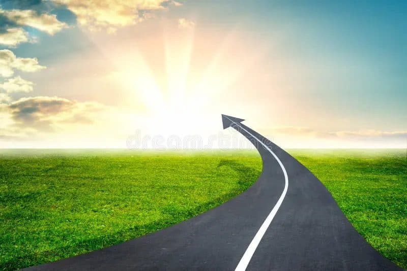 A paved road curving and rising into an upward-pointing arrow beneath a sunrise over a grassy field.